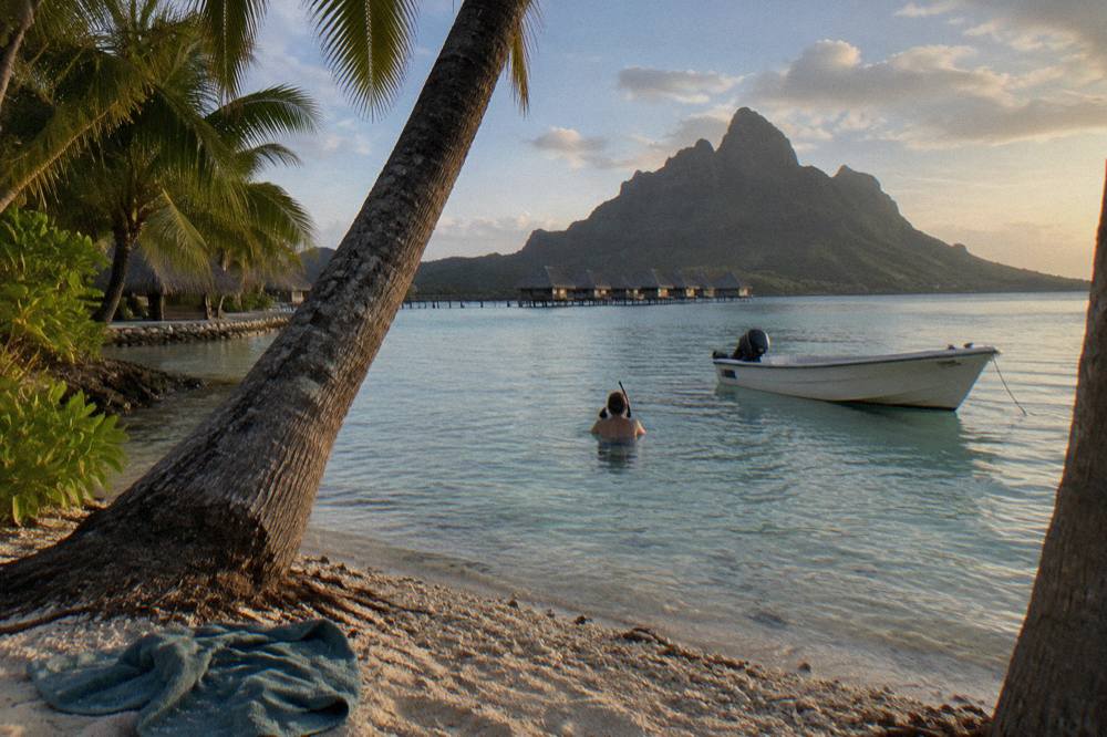 Snorkeler floating calmly in clear shallow lagoon water near a boat