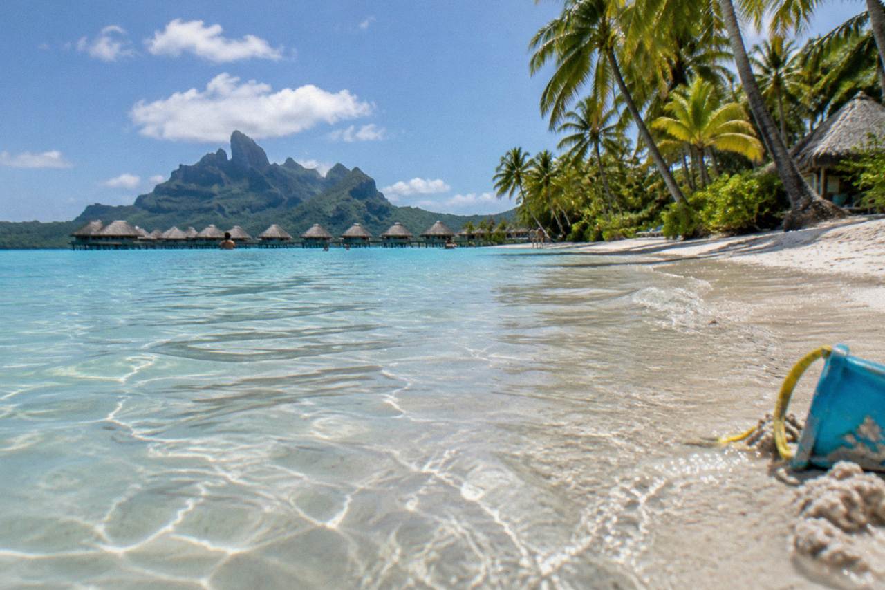 Calm turquoise lagoon water over pale sand in Bora Bora