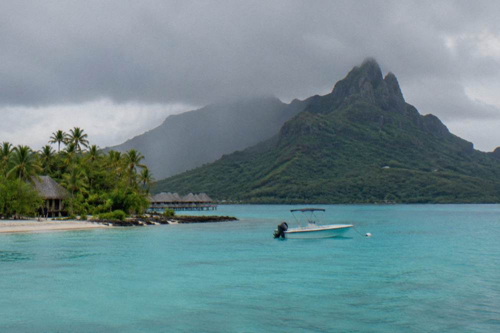 Small boat anchored in bright turquoise lagoon water near a green island