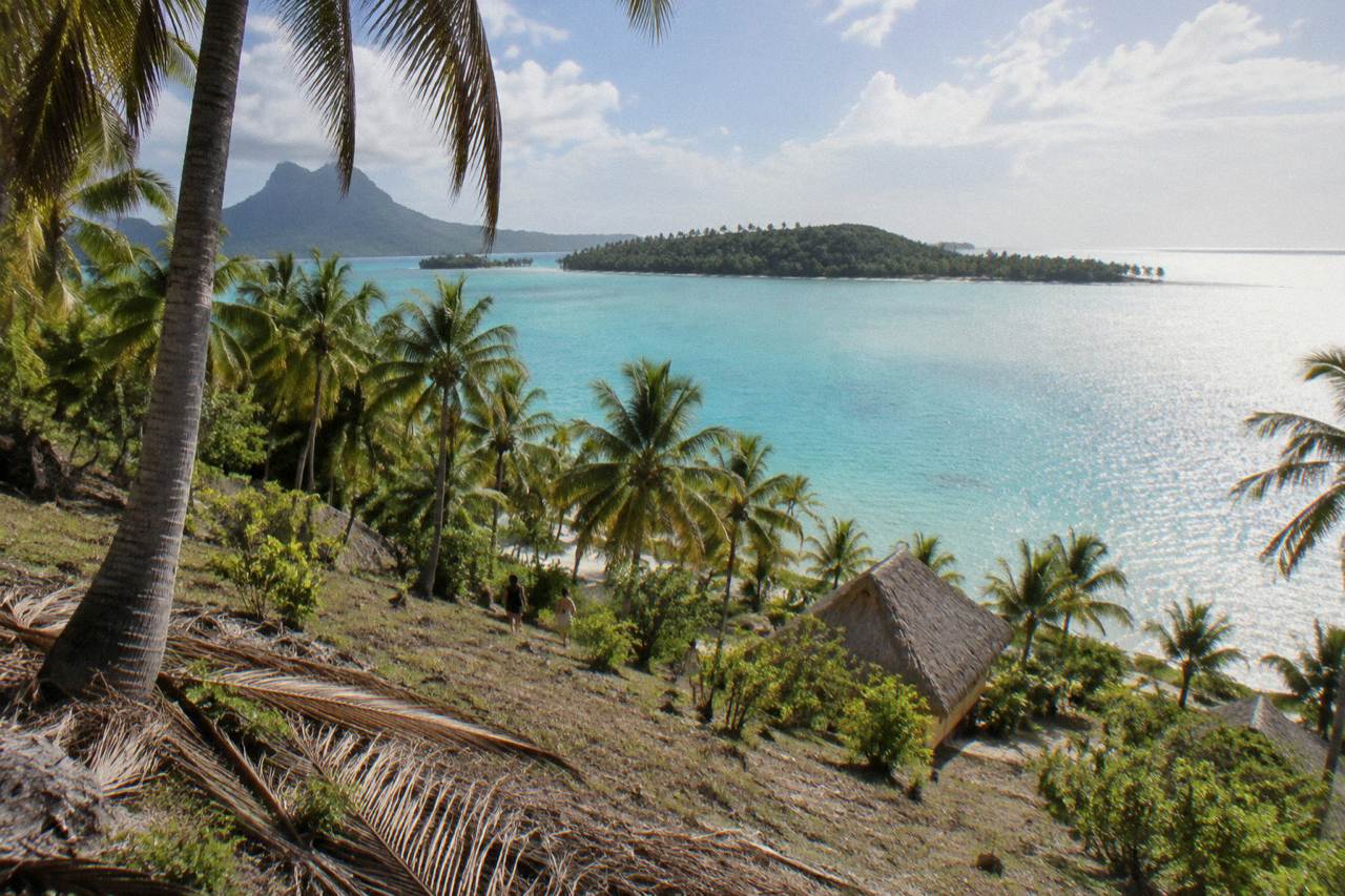 Turquoise lagoon water and green palm covered motu under a bright sky