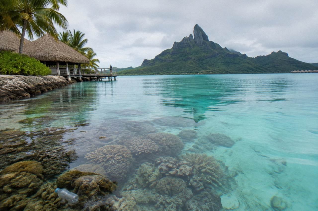 Coral reef and calm turquoise lagoon water below a mountain island