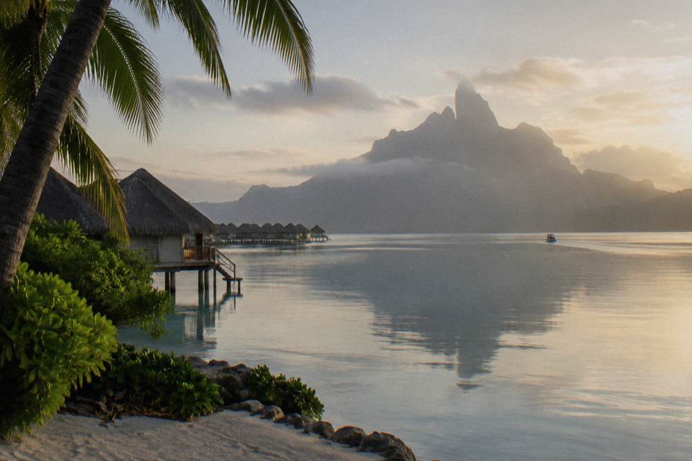 Smooth early morning lagoon water with mountain peaks rising above the reef