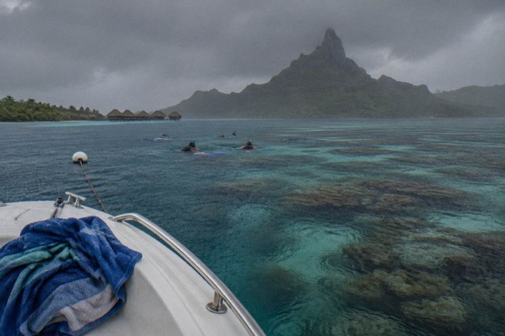 Small boat with snorkelers anchored near a coral garden in the Bora Bora lagoon