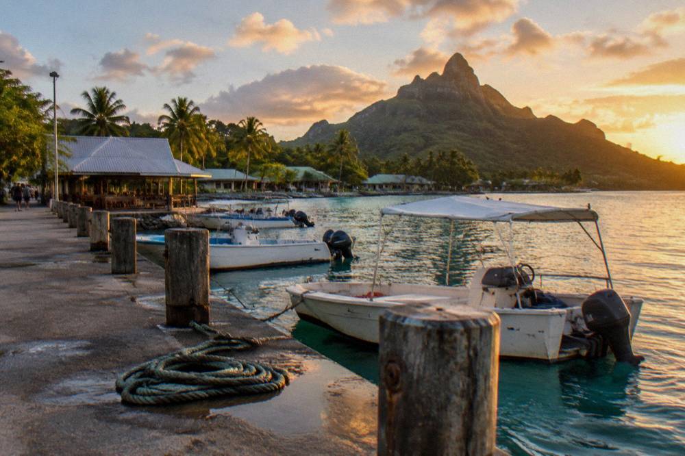A village waterfront on a tropical lagoon with small boats moored along a quay