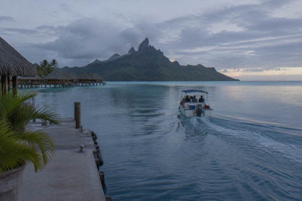 Small snorkel boat crossing flat morning water toward a reef pass