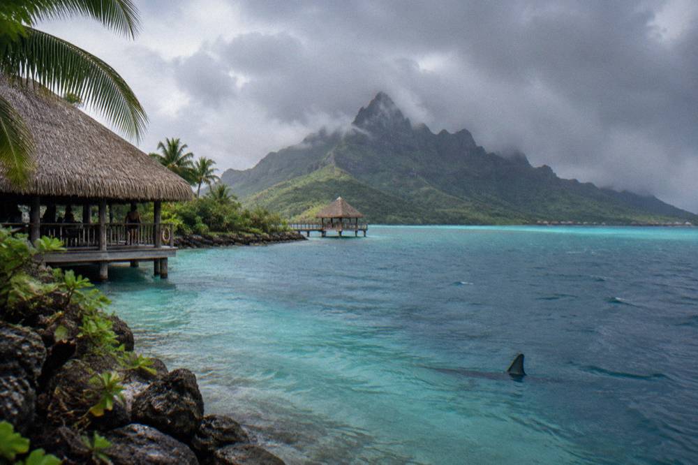 Dramatic clouds over the Bora Bora lagoon with dark green peaks partly in mist