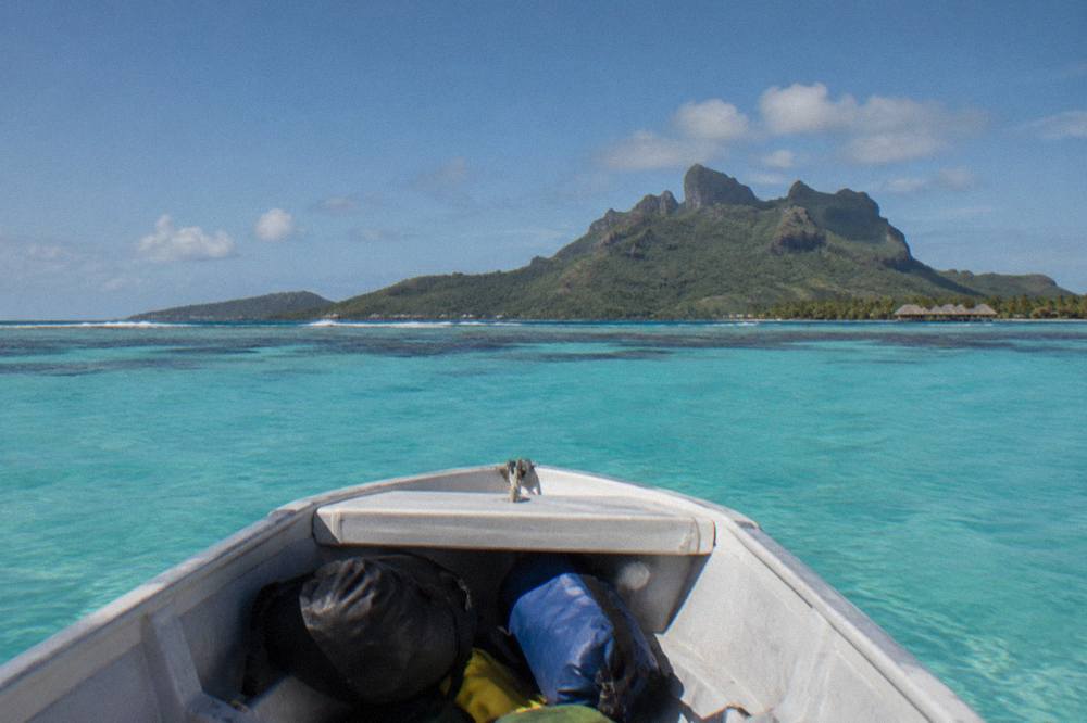 Small boat crossing turquoise lagoon water toward a coral reef