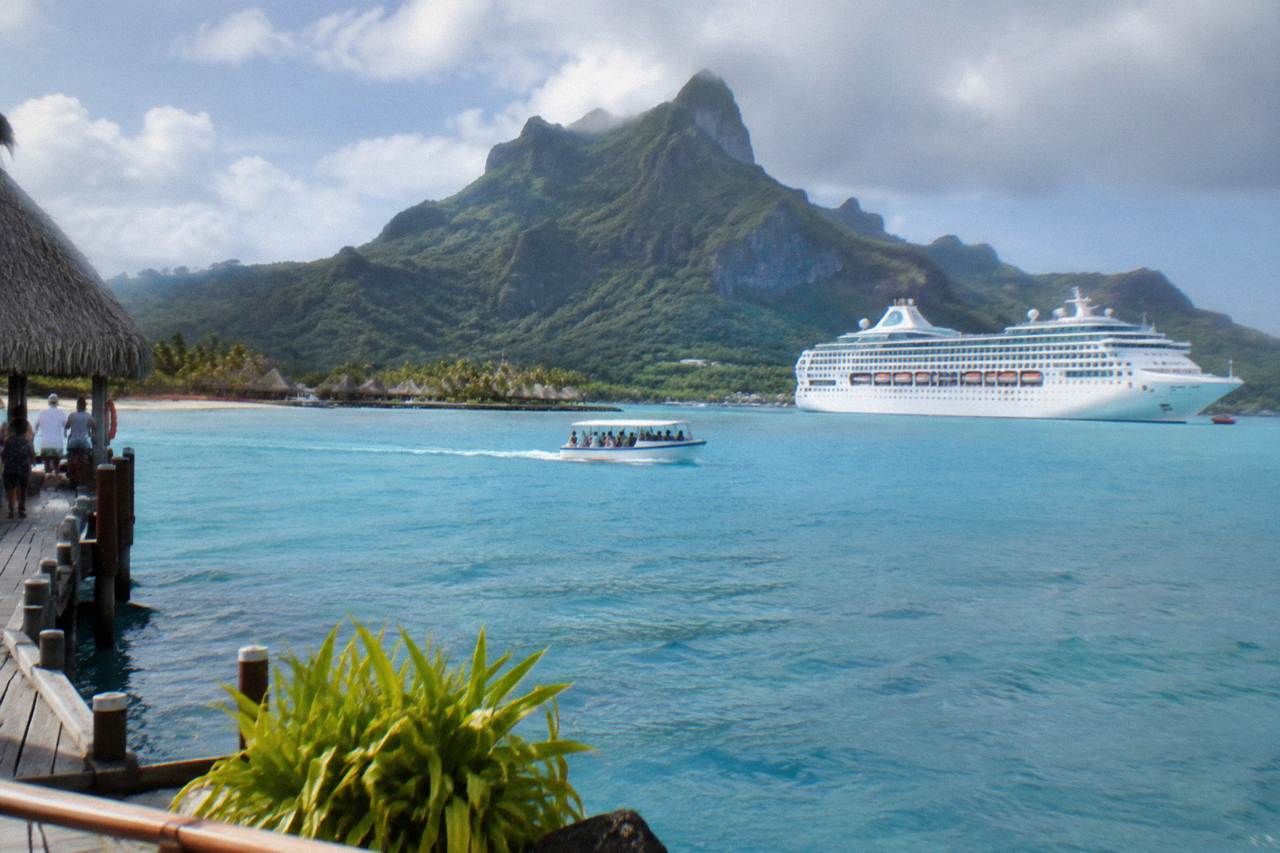 Cruise ship anchored in a calm turquoise lagoon with a green volcanic peak behind it