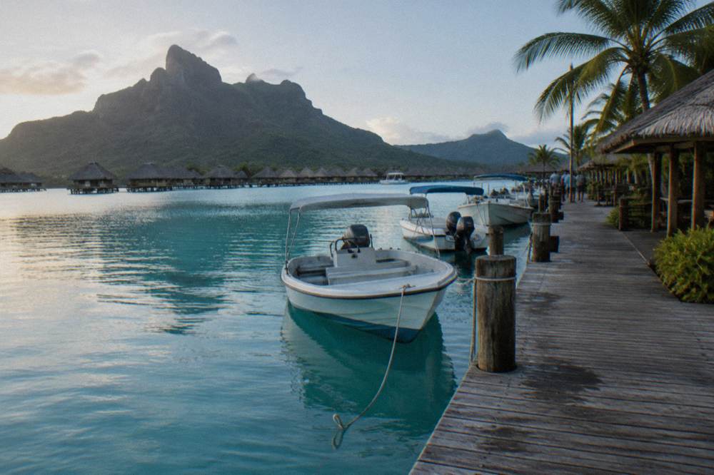 A wooden quay beside calm lagoon water with small boats tied alongside