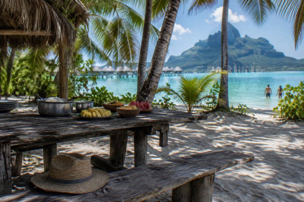 A picnic table with a served lunch under palm shade on a small sandy islet