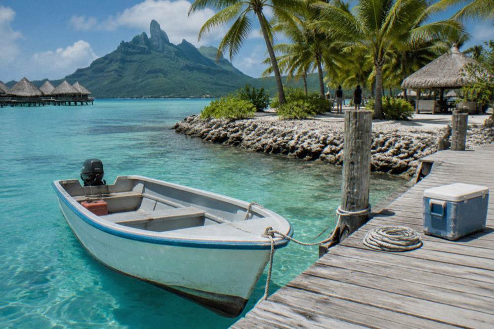 A small boat moored beside a wooden jetty on a Bora Bora motu