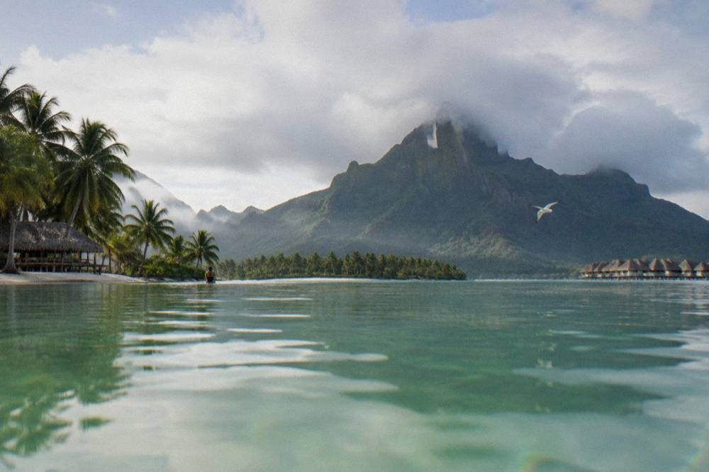 Morning light on calm lagoon water with Bora Bora's green peaks in the distance