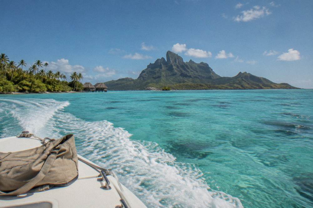A private boat cruising across open turquoise lagoon water toward reef islets