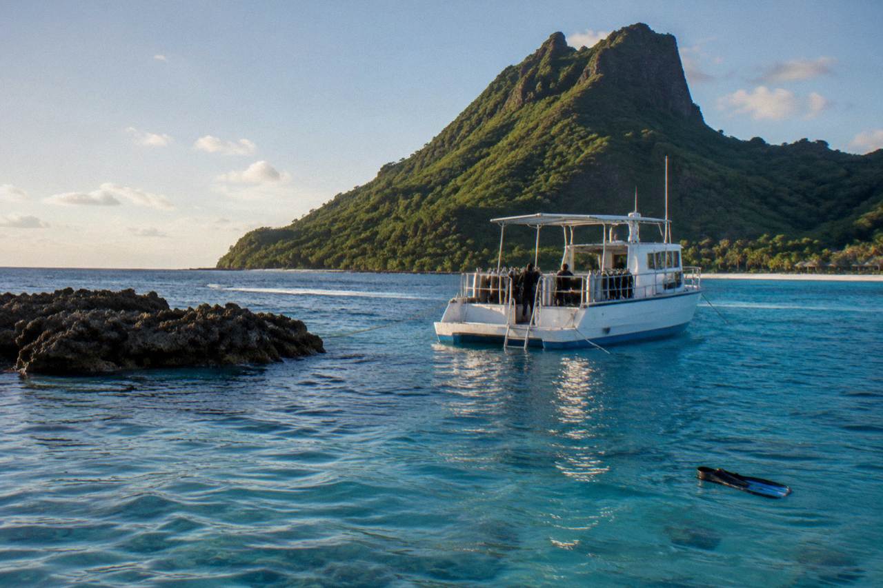 Turquoise Bora Bora lagoon water with a boat anchored near a coral reef