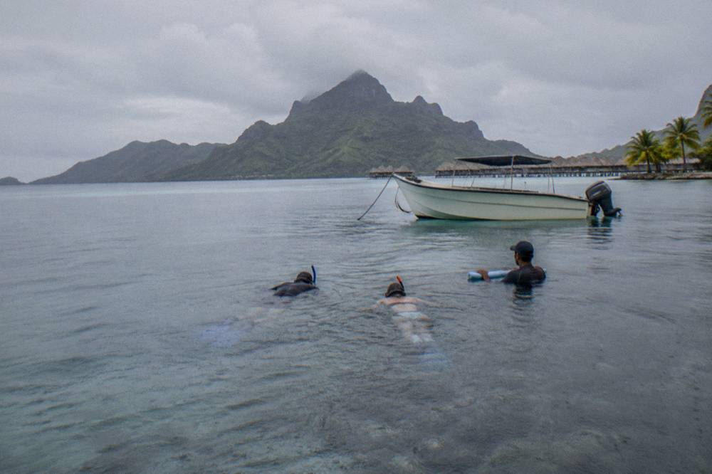 Snorkelers in calm water beside a small anchored lagoon boat