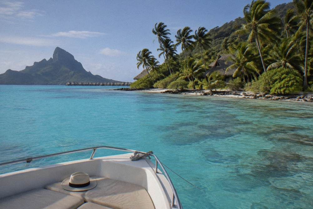 Small boat anchored in sheltered turquoise water beside a coral reef