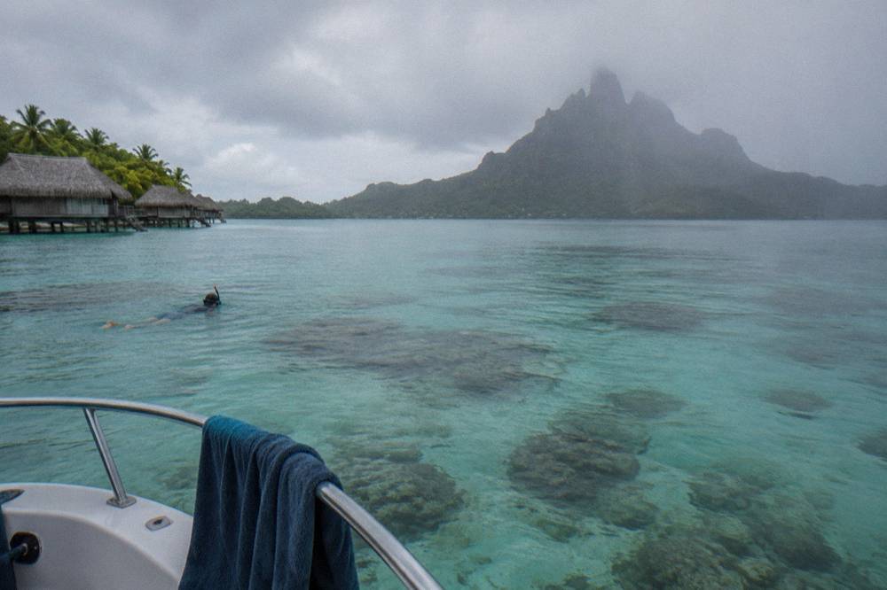 Snorkel boat anchored beside a shallow coral patch inside a turquoise lagoon