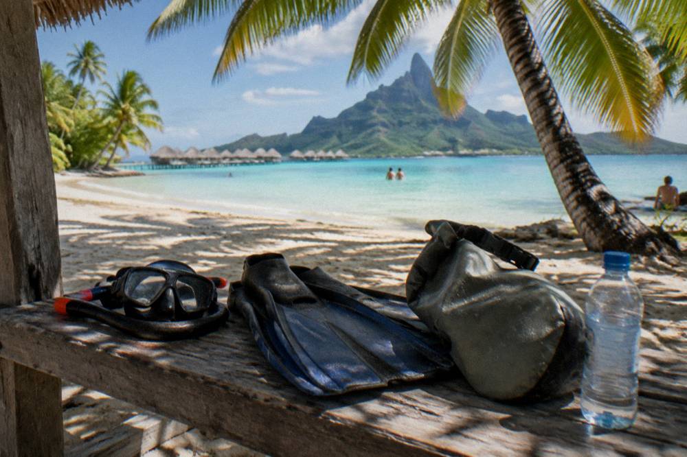Snorkel gear and dry bag arranged on a boat bench beside turquoise lagoon water