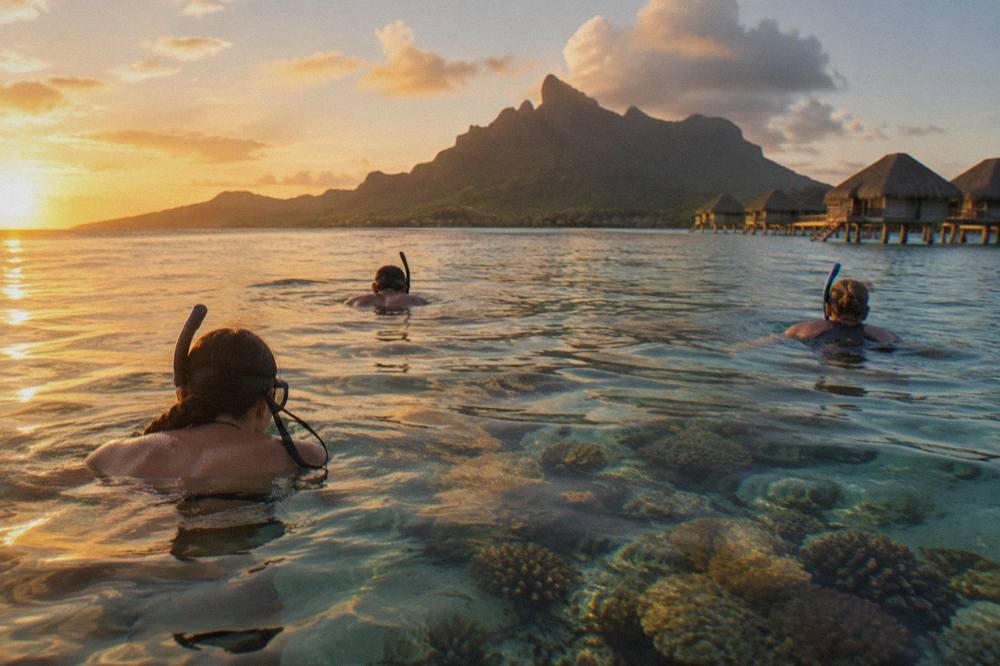 Snorkelers floating over a bright coral garden in clear turquoise lagoon water