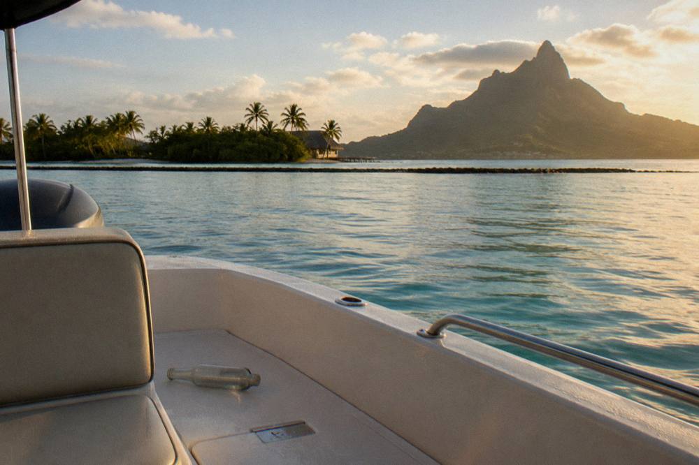 A private motor boat drifting near a reef line inside a wide calm lagoon