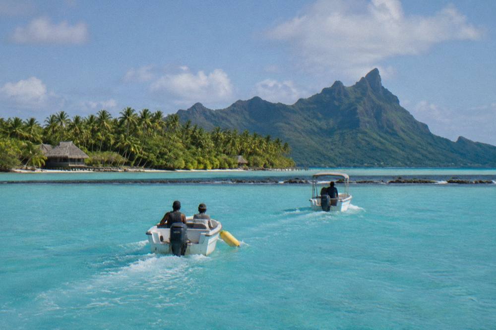 Two small motorboats crossing calm turquoise lagoon water toward a coral reef