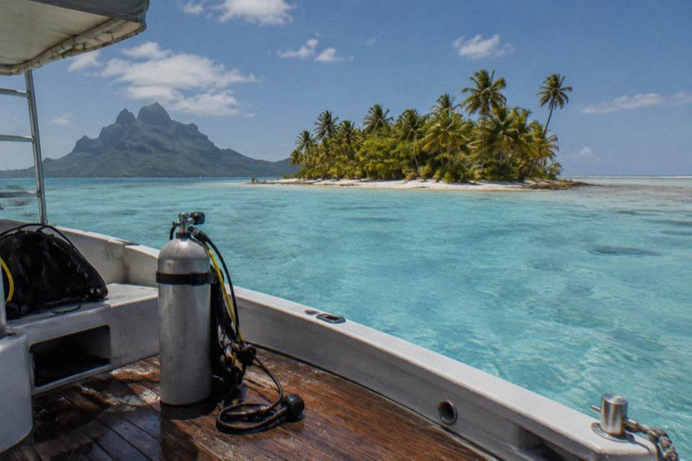A small boat anchored in shallow turquoise lagoon water beside a coral reef
