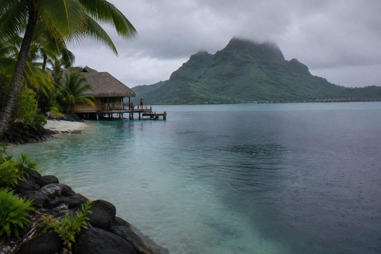 Calm turquoise lagoon water near a coral reef in Bora Bora with a green island rising behind it