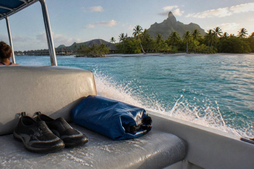 Water shoes and a folded dry bag on the bench seat of a lagoon boat