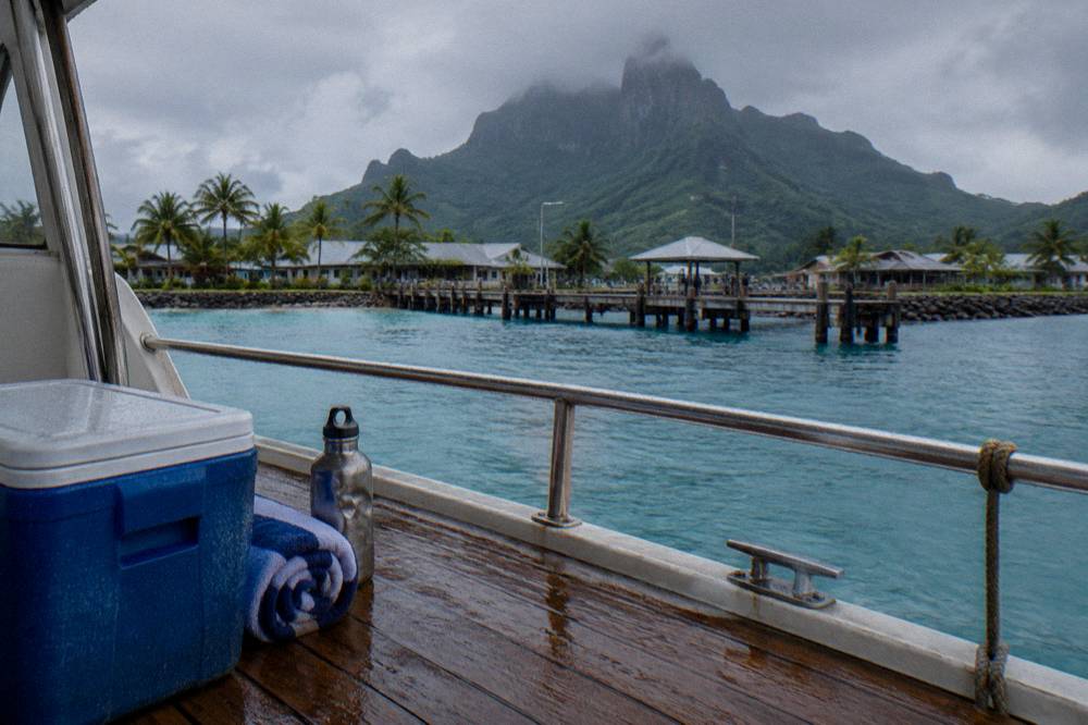 A rolled towel and a water bottle stowed beside a cooler on a lagoon tour boat